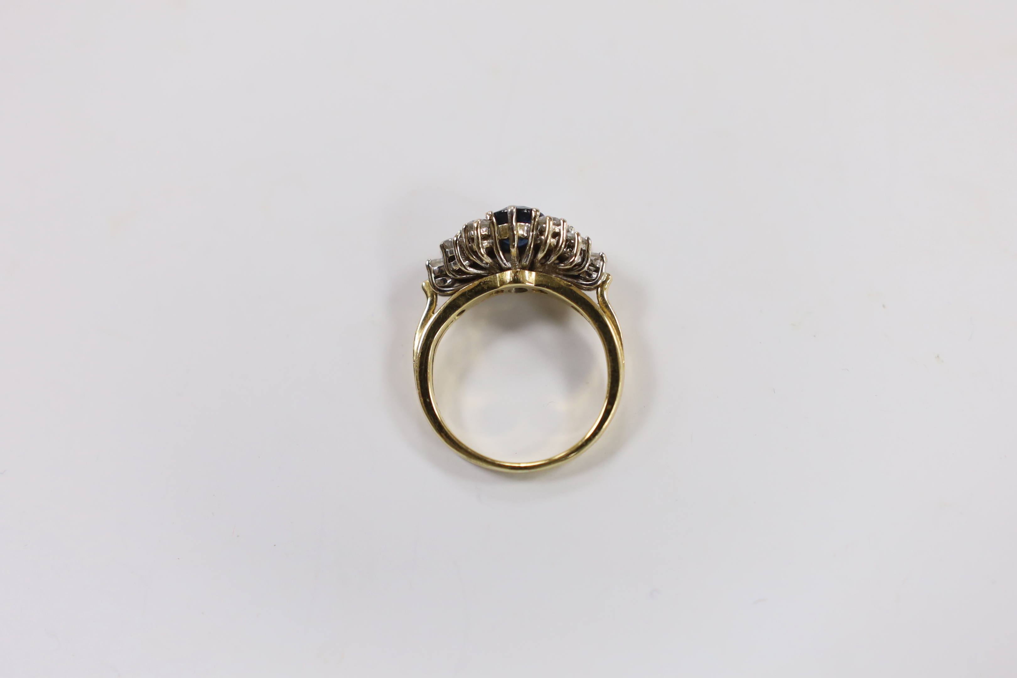 A modern 18ct gold and single stone oval cut sapphire set dress ring, with twelve stone diamond set shoulders, size O, gross weight 6.7 grams.